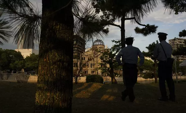 Police officers patrol at the Peace Memorial Park with the Atomic Bomb Dome in the background in Hiroshima, Tuesday, Aug. 5, 2025 on the eve of the 80th anniversary of the atomic bombing. (AP Photo/Louise Delmotte)