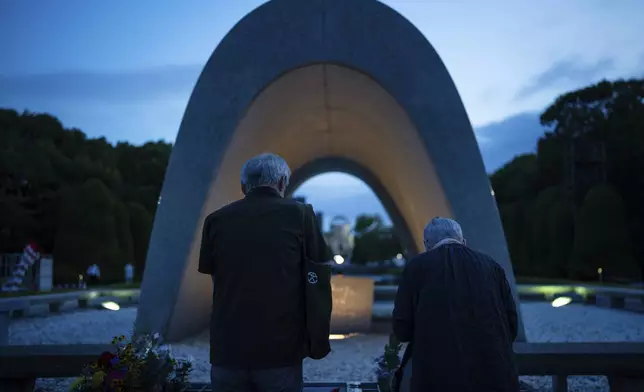 People pray for the atomic bomb victims in front of the Memorial Cenotaph ahead of the memorial service to mark the 80th anniversary of the WWII U.S. atomic bombing in Hiroshima, Wednesday, Aug. 6, 2025, in Japan. (AP Photo/Louise Delmotte)