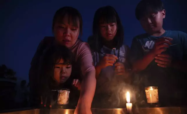 Visitors light incense sticks and pray at the Peace Memorial Park ahead of the memorial service to mark the 80th anniversary of the WWII U.S. atomic bombing in Hiroshima, Wednesday, Aug. 6, 2025, in Japan. (AP Photo/Louise Delmotte)