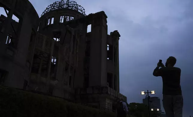 A visitor takes photographs of the Atomic Bomb Dome in Hiroshima, Monday, August 4, 2025, as Japan will mark 80th anniversary of the WWII U.S. atomic bombing on August 6. (AP Photo/Louise Delmotte)
