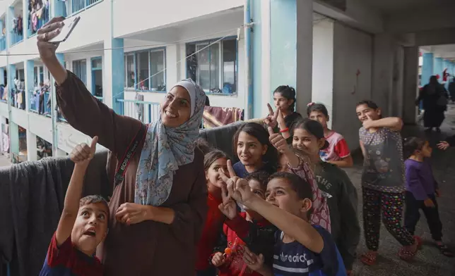 Freelance journalist Mariam Dagga, 33, who had been working with The Associated Press and other outlets during the Gaza war, takes a selfie surrounded by children at a school used to shelter displaced Palestinians in Khan Younis, southern Gaza Strip, Oct. 31, 2023. Dagga was one of several journalists killed, along with other people, in Israeli strikes on Nasser Hospital in Khan Younis on Monday, Aug. 25, 2025. (AP Photo/Jehad Alshrafi)