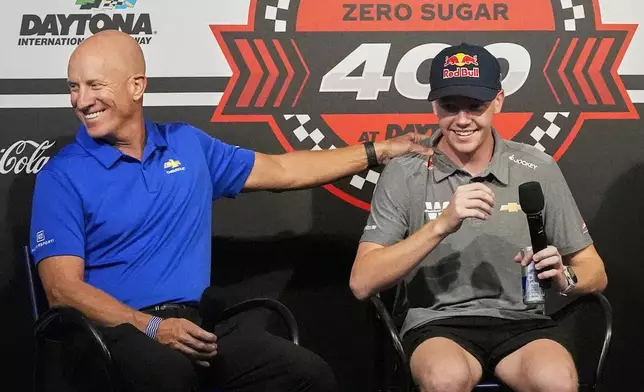 Dr. Eric Warren, left, vice president of global motorsports competition of General Motors, jokes with driver Connor Zilisch during an auto racing news conference at Daytona International Speedway, Saturday, Aug. 23, 2025, in Daytona Beach, Fla. (AP Photo/John Raoux)