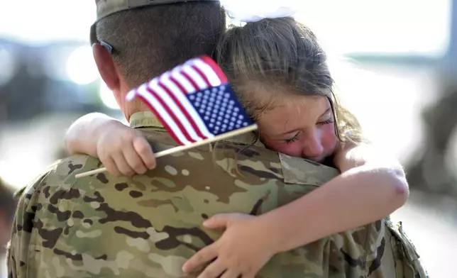 FILE - U.S. Army Staff Sgt. Jason Dinkins with the 3rd Combat Aviation Brigade is hugged by his daughter Olivia Chastain after a welcome home ceremony, Tuesday, June 11, 2013 at Hunter Army Airfield in Savannah, Ga. (AP Photo/Stephen Morton, file)