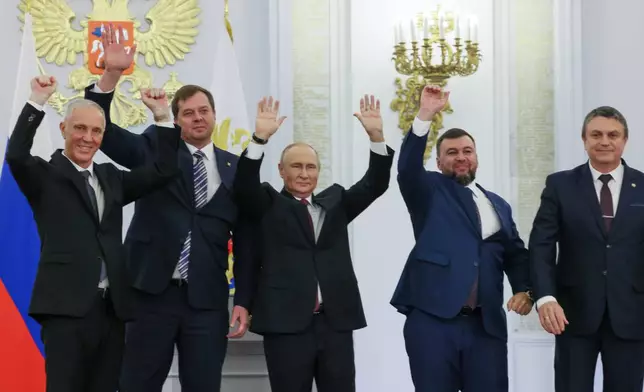 FILE - Russian President Vladimir Putin, center, with from left, Moscow-appointed head of Kherson Region Vladimir Saldo, Moscow-appointed head of Zaporizhzhia region Yevgeny Balitsky, Denis Pushilin, the leader of the Donetsk People's Republic and Leonid Pasechnik, leader of self-proclaimed Luhansk People's Republic wave during a ceremony to sign the treaties for four regions of Ukraine to join Russia, at the Kremlin, Moscow, Sept. 30, 2022. The signing of the treaties making the four regions part of Russia follows the completion of the Kremlin-orchestrated "referendums." (Mikhail Metzel, Sputnik, Kremlin Pool Photo via AP, File)