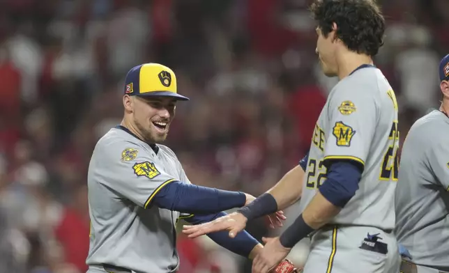 Milwaukee Brewers' Caleb Durbin, left, and Milwaukee Brewers' Christian Yelich, right, celebrate at the conclusion of a baseball game game against the Cincinnati Reds, Friday, Aug. 15, 2025, in Cincinnati. (AP Photo/Kareem Elgazzar)