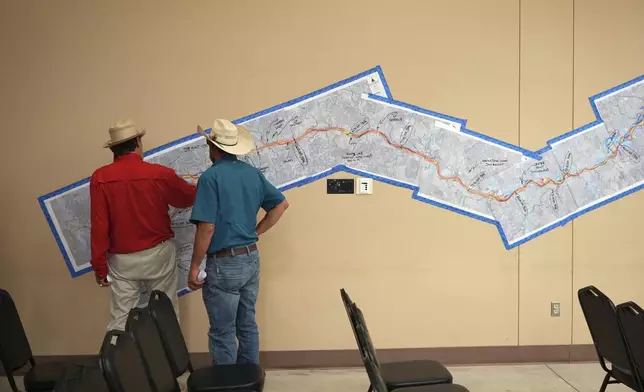 Attendees look at a marked up map of the Guadalupe River during a Senate and House Select Committees on Disaster Preparedness and Flooding public hearing, in Kerrville, Texas, Thursday, July 31, 2025. (AP Photo/Eric Gay)