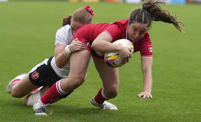Taylor Perry of Canada, right, goes over the line to score a try despite a tackle from Lisa Neumann of Wales, during the pool B match at the 2025 Women's Rugby World Cup between Canada and Wales, in Manchester, England, Saturday, Aug. 30, 2025. (AP Photo/Dave Shopland)