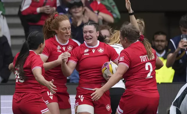 Alysha Corrigan of Canada holds the ball as she celebrates with teammates after scoring a try during the pool B match at the 2025 Women's Rugby World Cup between Canada and Wales, in Manchester, England, Saturday, Aug. 30, 2025. (AP Photo/Dave Shopland)