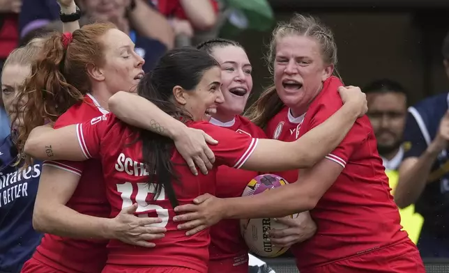 Alysha Corrigan of Canada, second right, holds the ball as she celebrates with teammates after scoring a try during the pool B match at the 2025 Women's Rugby World Cup between Canada and Wales, in Manchester, England, Saturday, Aug. 30, 2025. (AP Photo/Dave Shopland)