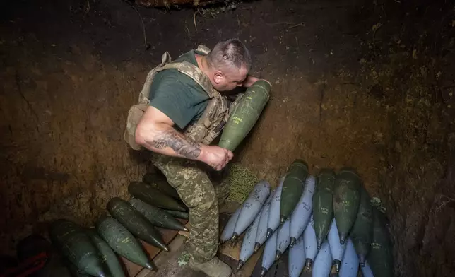 A soldier of Ukraine's 30th Mechanized Brigade prepares to fire a howitzer towards Russian positions on the front line near near Kharkiv, Ukraine, Wednesday, Aug. 13, 2025. (AP Photo/Andrii Marienko)