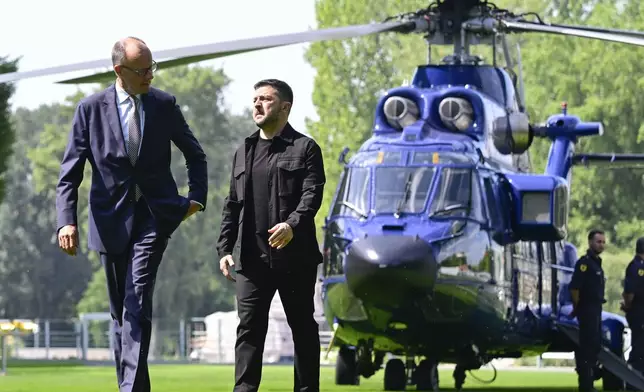 Ukrainian President Volodymyr Zelenskyy, front right, is welcomed by German Chancellor Friedrich Merz, left, upon arrival in the garden of the chancellery in Berlin, Germany, Wednesday, Aug. 13, 2025 to join a video conference of European leaders with the US President on the Ukraine war. (John MacDougall/Pool Photo via AP)
