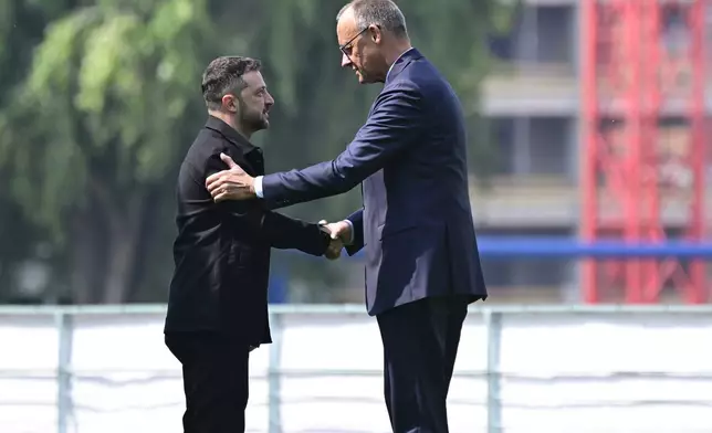 Ukrainian President Volodymyr Zelenskyy, left, is welcomed by German Chancellor Friedrich Merz upon arrival in the garden of the chancellery in Berlin, Germany, Wednesday, Aug. 13, 2025 to join a video conference of European leaders with the US President on the Ukraine war. (John MacDougall/Pool Photo via AP)