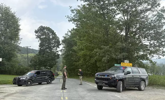 Police officers block the street leading to where two Pennsylvania state troopers were ambushed and shot Thursday, Aug. 7, 2025, near the village of Thompson in Susquehanna County, Pa. (AP Photo/Aimee Dilger)