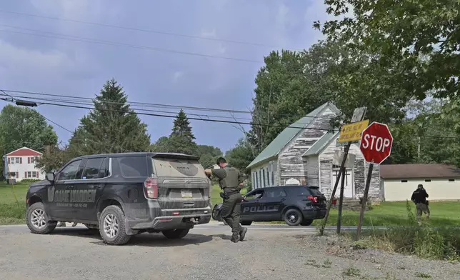 Police officers block the street leading to where two Pennsylvania state troopers were ambushed and shot Thursday, Aug. 7, 2025, near the village of Thompson in Susquehanna County, Pa. (AP Photo/Aimee Dilger)