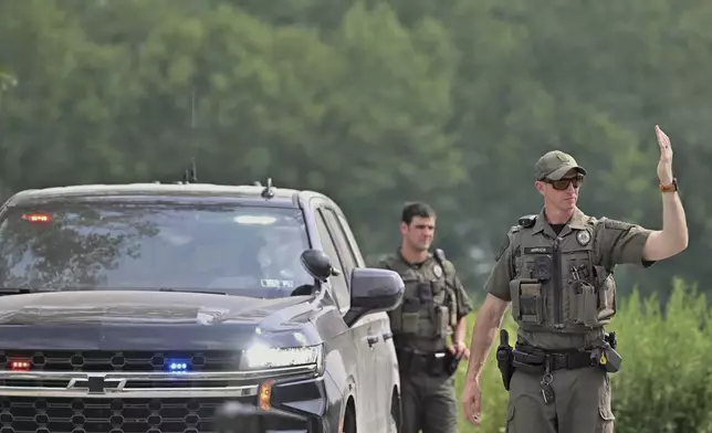 Police officers block the street leading to where two Pennsylvania state troopers were ambushed and shot Thursday, Aug. 7, 2025, near the village of Thompson in Susquehanna County, Pa. (AP Photo/Aimee Dilger)