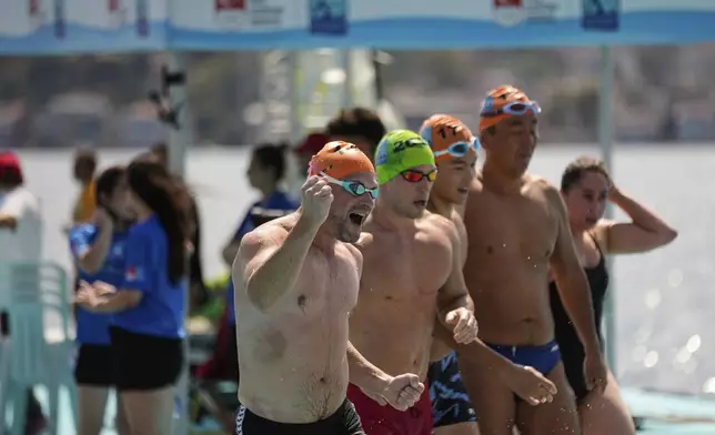 Competitors celebrate after finishing a 6.5 km swimming race across the Bosphorus Strait, from the Asian side to the European side, in Istanbul, Turkey, Sunday, Aug. 24, 2025. (AP Photo/Khalil Hamra)