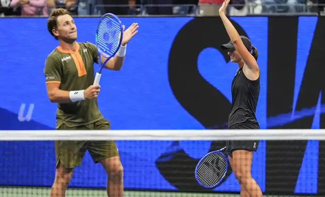 Iga Swiatek, right of Poland, and Casper Ruud, left, of Norway, wave at fans after winning the mixed doubles semi final at the U.S. Open tennis championships, Wednesday, Aug. 20, 2025, in New York. (AP Photo/Yuki Iwamura)