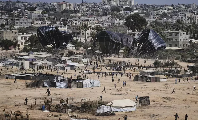 Palestinians rush to collect humanitarian aid airdropped into Zawaida in central Gaza Strip, Thursday, July 31, 2025. (AP Photo/Abdel Kareem Hana)