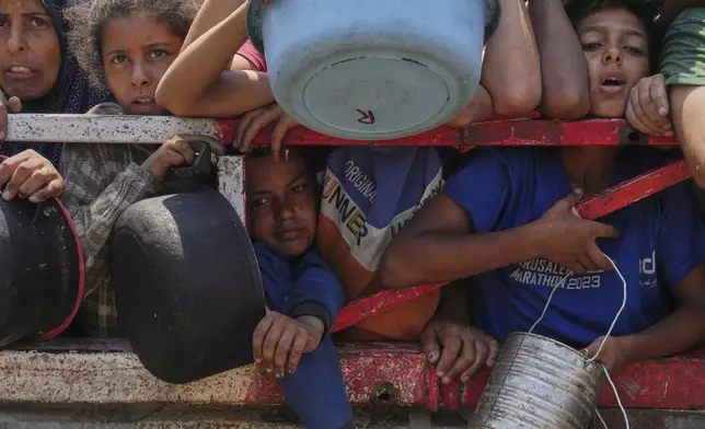 Palestinians struggle to get donated food at a community kitchen, in Gaza City, northern Gaza Strip, Saturday, July 26, 2025. (AP Photo/Abdel Kareem Hana)