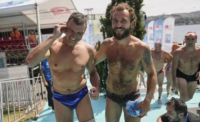 Ukrainian war veterans Pavlo Tovstyk, left, and Oleh Tserkovnyi, smile after completing a 6.5km swimming race across the Bosporus Strait, from the Asian side to the European side, in Istanbul, Turkey, Sunday, Aug. 24, 2025. (AP Photo/Khalil Hamra)