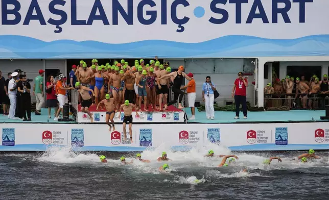 Competitors jump into the water at the start of a 6.5km swimming race across the Bosporus Strait, from the Asian side to the European side, in Istanbul, Turkey, Sunday, Aug. 24, 2025. (AP Photo/Khalil Hamra)