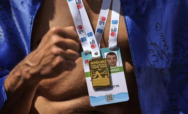 Ukrainian war veteran Pavlo Tovstyk dons a medal for his participation in a 6.5km swimming race across the Bosporus Strait, in Istanbul, Turkey, Sunday, Aug. 24, 2025. (AP Photo/Khalil Hamra)