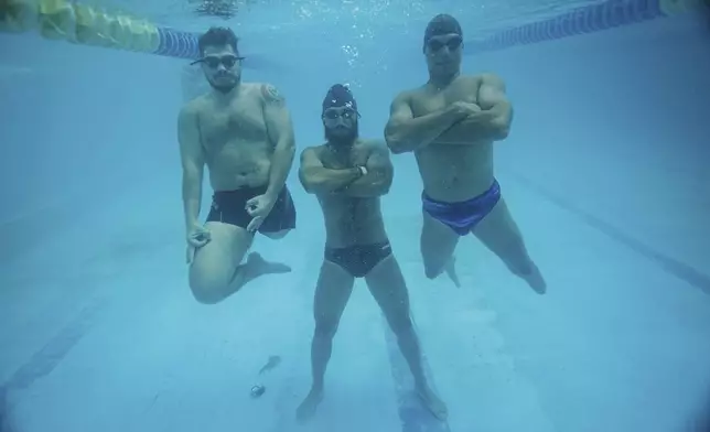 Ukrainian war veterans Oleksandr Dashko, from left, Oleh Tserkovnyi and Pavlo Tovstyk, pose for an underwater photo in a pool in Kyiv, Ukraine, Tuesday, Aug. 12, 2025, as they take a break from their training session for the upcoming 6.5km swimming race across the Bosporus Strait. (AP Photo/Evgeniy Maloletka)