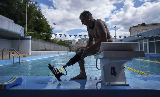 Ukrainian war veteran Pavlo Tovstyk removes his prosthesis in Kyiv, Ukraine, Tuesday, Aug. 12, 2025, as he prepares to train for an upcoming 6.5km swimming race across the Bosporus Strait. (AP Photo/Evgeniy Maloletka)