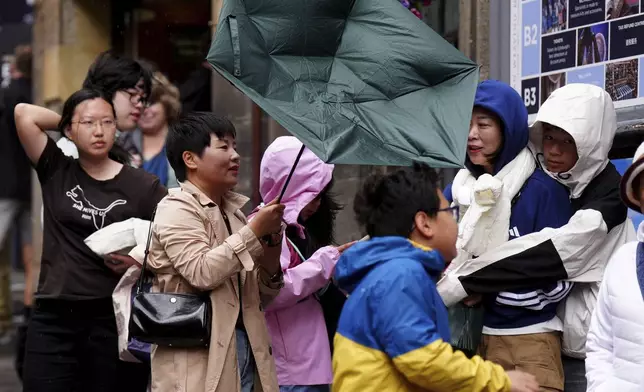 Members of the public battle against the wind as they walk along the Royal Mile, in Edinburgh, Scotland, Monday Aug. 4, 2025, as weather warnings are coming into force with Storm Floris expected to cause severe travel disruption to road, air and ferry services, and close bridges. (Jane Barlow/PA via AP)