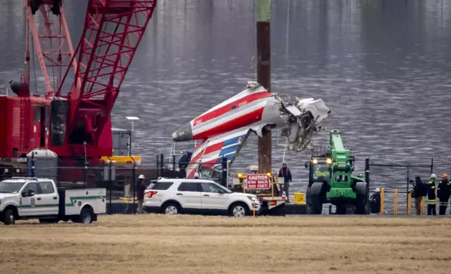 FILE - A crane offloads a piece of wreckage from a salvage vessel onto a flatbed truck, near the wreckage site in the Potomac River of a mid-air collision between an American Airlines jet and a Black Hawk helicopter, at Ronald Reagan Washington National Airport, Feb. 5, 2025, in Arlington, Va. (AP Photo/Ben Curtis, File)
