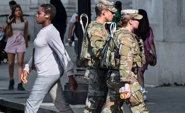 National Guard personnel keep watch as travelers arrive at the entrance to Union Station near the Capitol, in Washington, Thursday, Aug. 14, 2025. (AP Photo/J. Scott Applewhite)