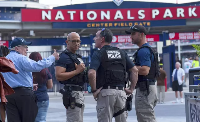Department of Homeland Security police officers interact with people arriving at Nationals Park during a baseball game between the Washington Nationals and Philadelphia Phillies in Washington, Thursday, Aug. 14, 2025. (AP Photo/Jose Luis Magana)