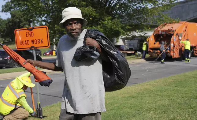 George, 67, walks away with what's left of his belongings, after the city put his mattress and other belongings in a dump truck, Thursday, Aug. 14, 2025, in Washington. (AP Photo/Jacquelyn Martin)