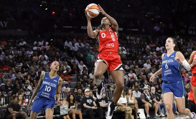 Las Vegas Aces guard Jackie Young (0) shoots a layup between Minnesota Lynx guard Courtney Williams (10) and Minnesota Lynx forward Bridget Carleton (6) during the first half of a WNBA basketball game Saturday, Aug. 2, 2025, in Las Vegas. (Steve Marcus/Las Vegas Sun via AP)