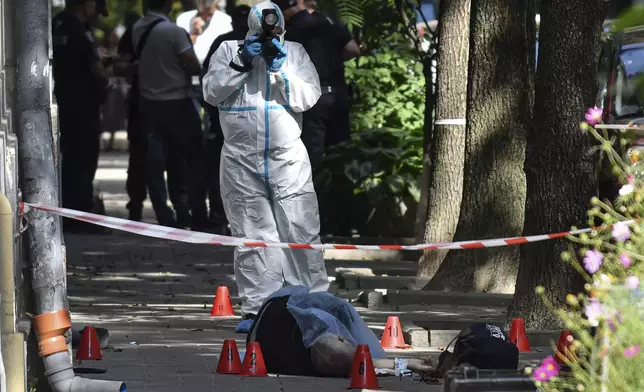 A forensic expert photographs a body of a former Ukrainian parliament speaker Andriy Parubiy, in Lviv, Ukraine, Saturday, Aug. 30, 2025. (AP Photo/Mykola Tys)