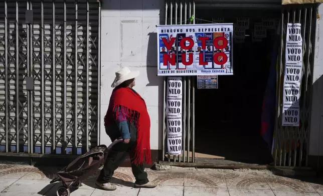 A woman walks past a campaign center for supporters of former President Evo Morales who are in favor or a null vote in the upcoming presidential election in El Alto, Bolivia, Tuesday, Aug. 12, 2025. (AP Photo/Natacha Pisarenko)