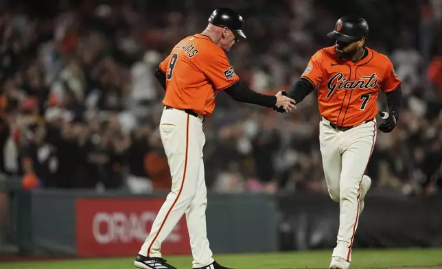 San Francisco Giants' Dominic Smith (7) celebrates with third base coach Matt Williams after hitting a two-run home run during the fourth inning of a baseball game against the Baltimore Orioles, Friday, Aug. 29, 2025, in San Francisco. (AP Photo/Godofredo A. Vásquez)