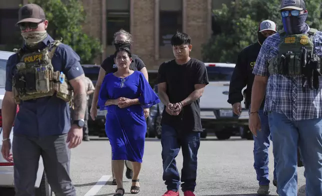 FILE - Federal agents escort a family to a transport bus after they were detained following an appearance at immigration court, July 22, 2025, in San Antonio, Texas. (AP Photo/Eric Gay, File)
