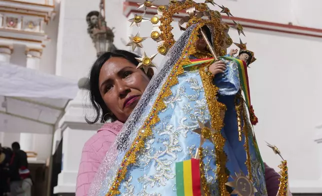 A woman holds a statue of the Virgin of Copacabana as she waits to take part in a procession honoring Bolivia's patroness, in Copacabana, Bolivia, Tuesday, Aug. 5, 2025. (AP Photo/Juan Karita)