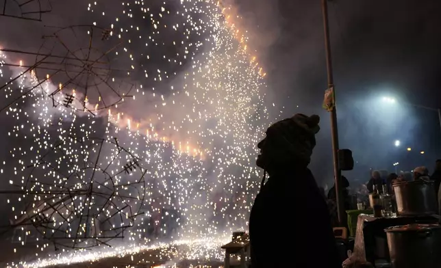 A man is silhouetted against a burst of fireworks during celebrations honoring Bolivia's patron saint, the Virgin of Copacabana, in Copacabana, Bolivia, Monday, Aug. 4, 2025. (AP Photo/Juan Karita)