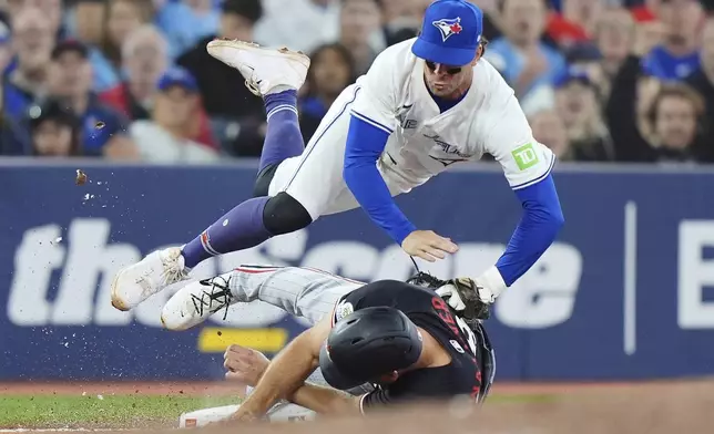Toronto Blue Jays third baseman Ernie Clement (top) tags out Minnesota Twins' Matt Wallner (38) at third base during eighth inning MLB baseball action in Toronto on Tuesday, August 26, 2025. (Frank Gunn/The Canadian Press via AP)