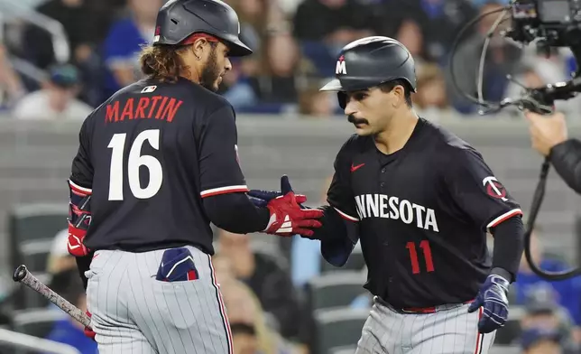 Minnesota Twins' Mickey Gasper, right, celebrates his solo home run against the Toronto Blue Jays with Austin Martin (16) during the ninth inning of a baseball game in Toronto on Tuesday, Aug. 26, 2025. (Frank Gunn/The Canadian Press via AP)