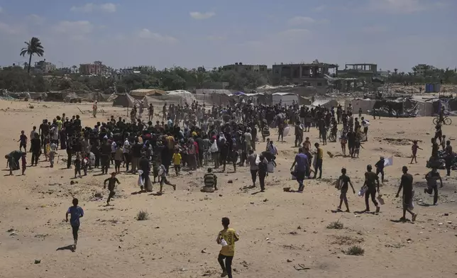Palestinians rush to collect humanitarian aid airdropped by parachutes into Deir Al-Balah, in the central Gaza Strip, Tuesday, Aug. 5, 2025. (AP Photo/Abdel Kareem Hana)