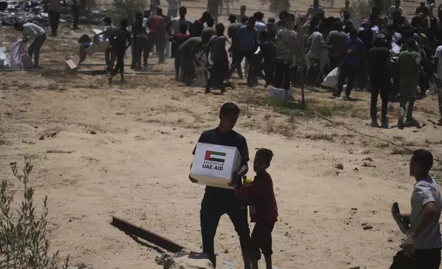 Palestinians collect humanitarian aid packages from the United Arab Emirates after they were airdropped into Deir Al-Balah, in the central Gaza Strip, Tuesday, Aug. 5, 2025. (AP Photo/Abdel Kareem Hana)