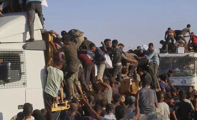 Palestinians struggle to get food and humanitarian aid from the back of a truck as it moves along the Morag corridor near Rafah, in the southern Gaza Strip, Monday, Aug. 4, 2025. (AP Photo/Mariam Dagga)