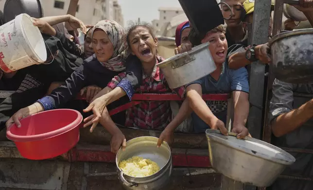 FILE - Palestinians struggle to get donated food at a community kitchen in Gaza City, northern Gaza Strip, Saturday, Aug. 16, 2025. (AP Photo/Jehad Alshrafi, File)