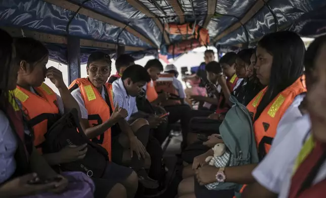 Students commute to school on Salvador Mitidieri's boat across the Amazon River from Tabatinga, Brazil, to Santa Rosa, Peru, Monday, Aug. 18, 2025. (AP Photo/Ivan Valencia)