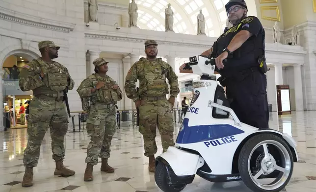 National Guard personnel talk to a member of the Amtrak Police, right, as travelers arrive at Union Station near the Capitol, in Washington, Friday, Aug. 15, 2025, in Washington. (AP Photo/Jacquelyn Martin)