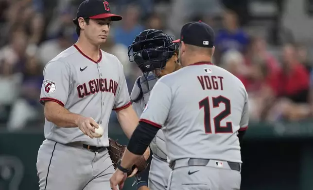 Cleveland Guardians starting pitcher Gavin Williams turns the ball over to manager Stephen Vogt (12) as he leaves the mound in the fourth inning of a baseball game against the Texas Rangers Sunday, Aug. 24, 2025, in Arlington, Texas. (AP Photo/Tony Gutierrez)