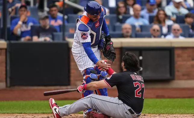 New York Mets catcher Luis Torrens (13) helps up Cleveland Guardians' Austin Hedges (27) after he ducked away from a pitch during the seventh inning of a baseball game against the Cleveland Guardians, Wednesday, Aug. 6, 2025, in New York. (AP Photo/Yuki Iwamura)